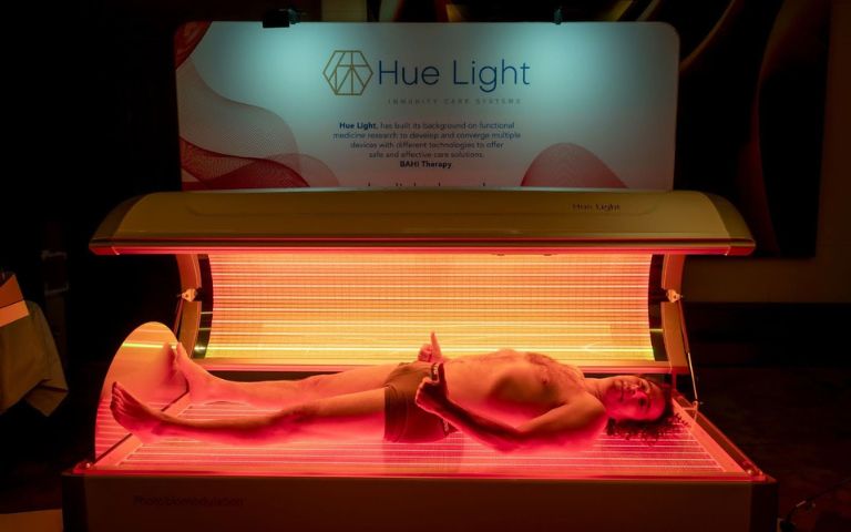 a guy lying in a red light therapy device